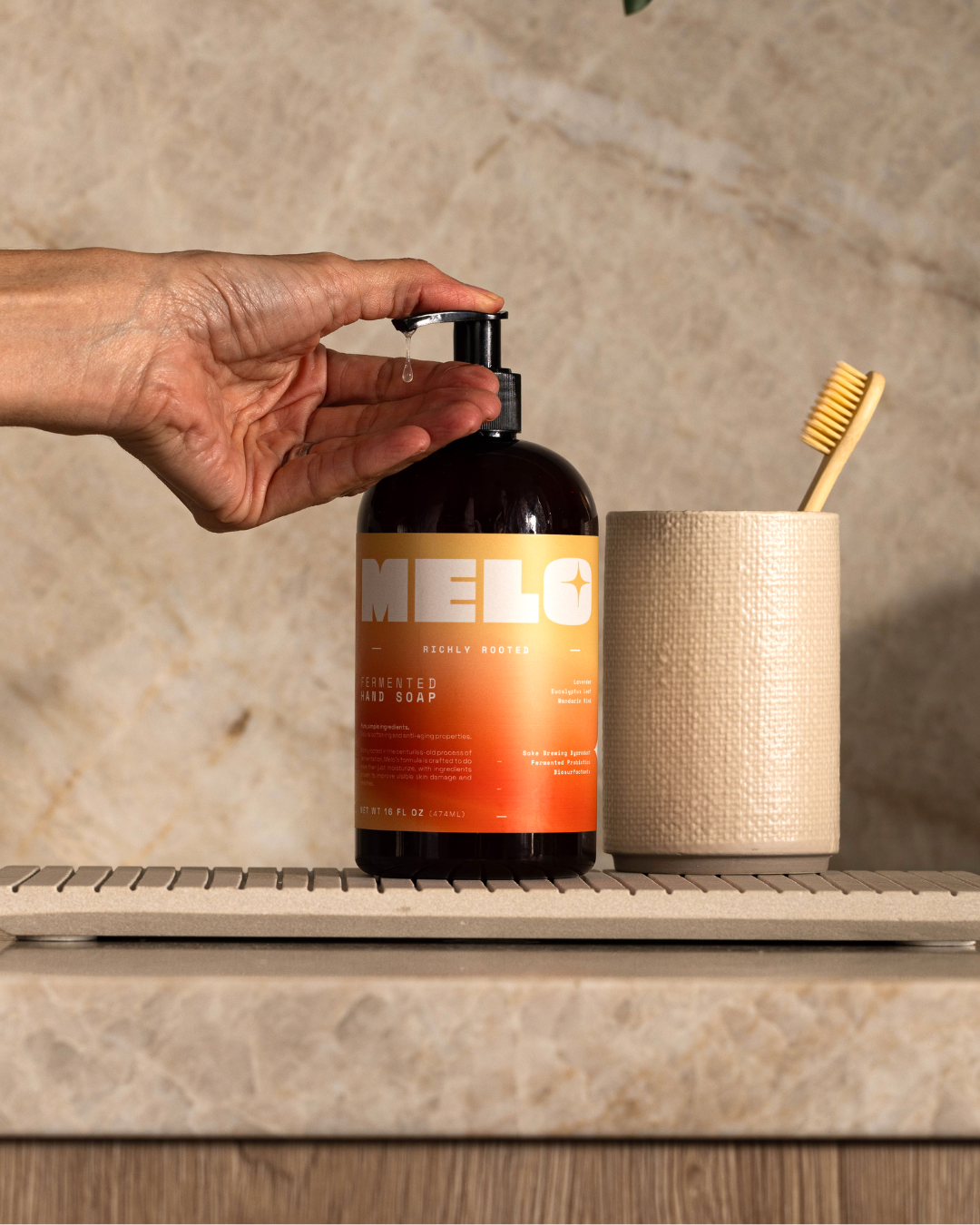 Hand pumping a bottle of MELO soap on a countertop