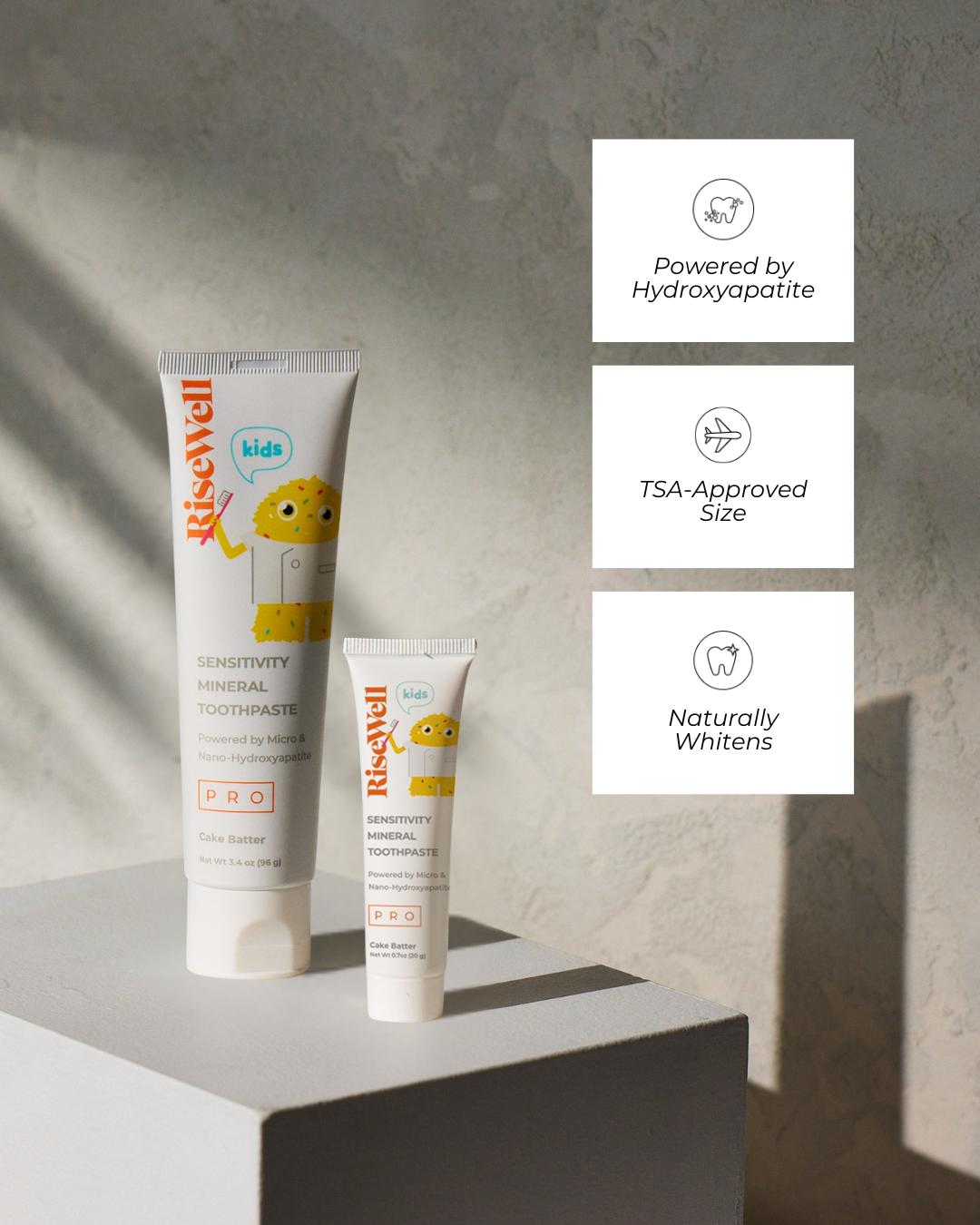 Two tubes of RiseWell Kids toothpaste on a gray surface with product features displayed.