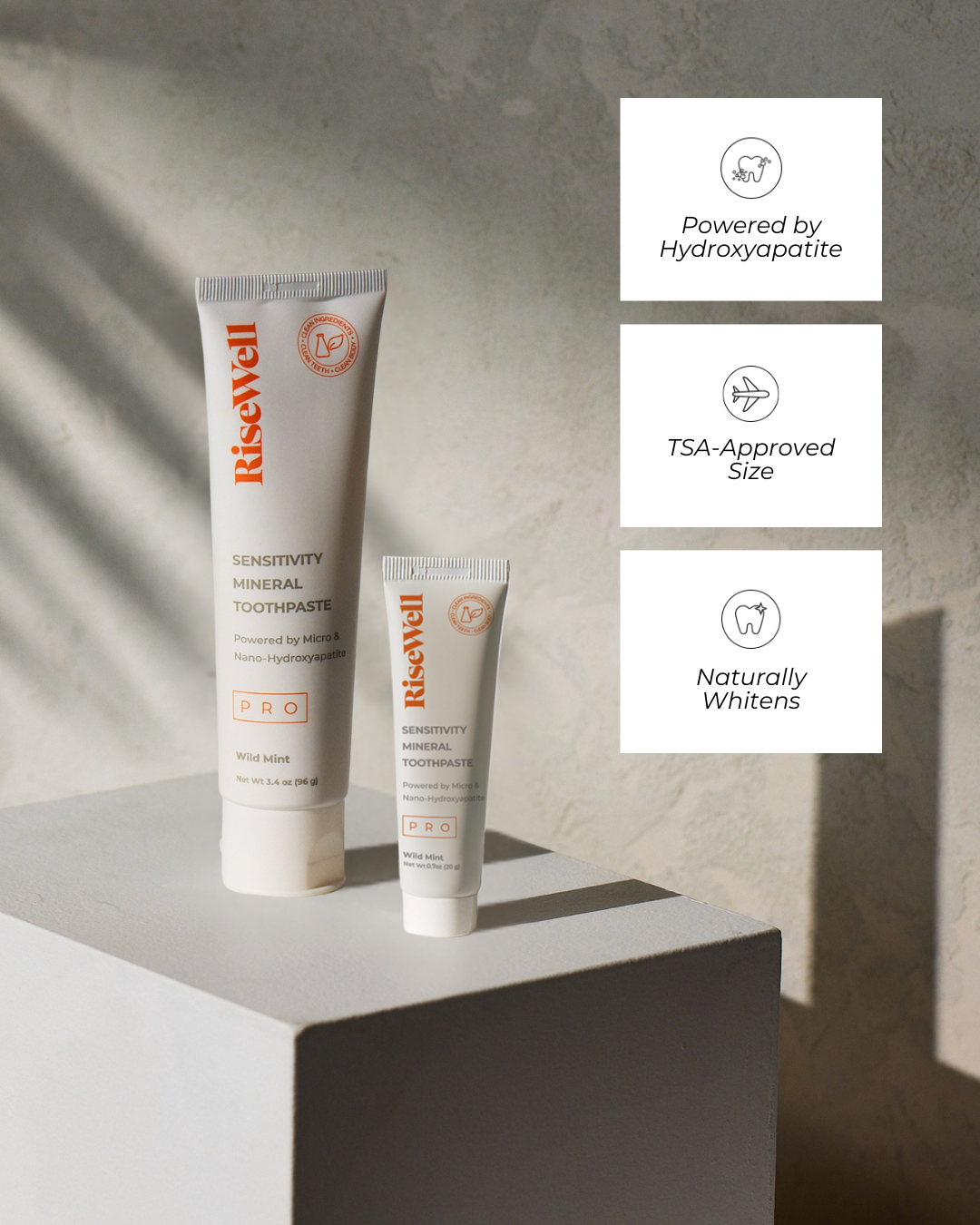 Two tubes of RiseWell toothpaste on a light surface with product features displayed.