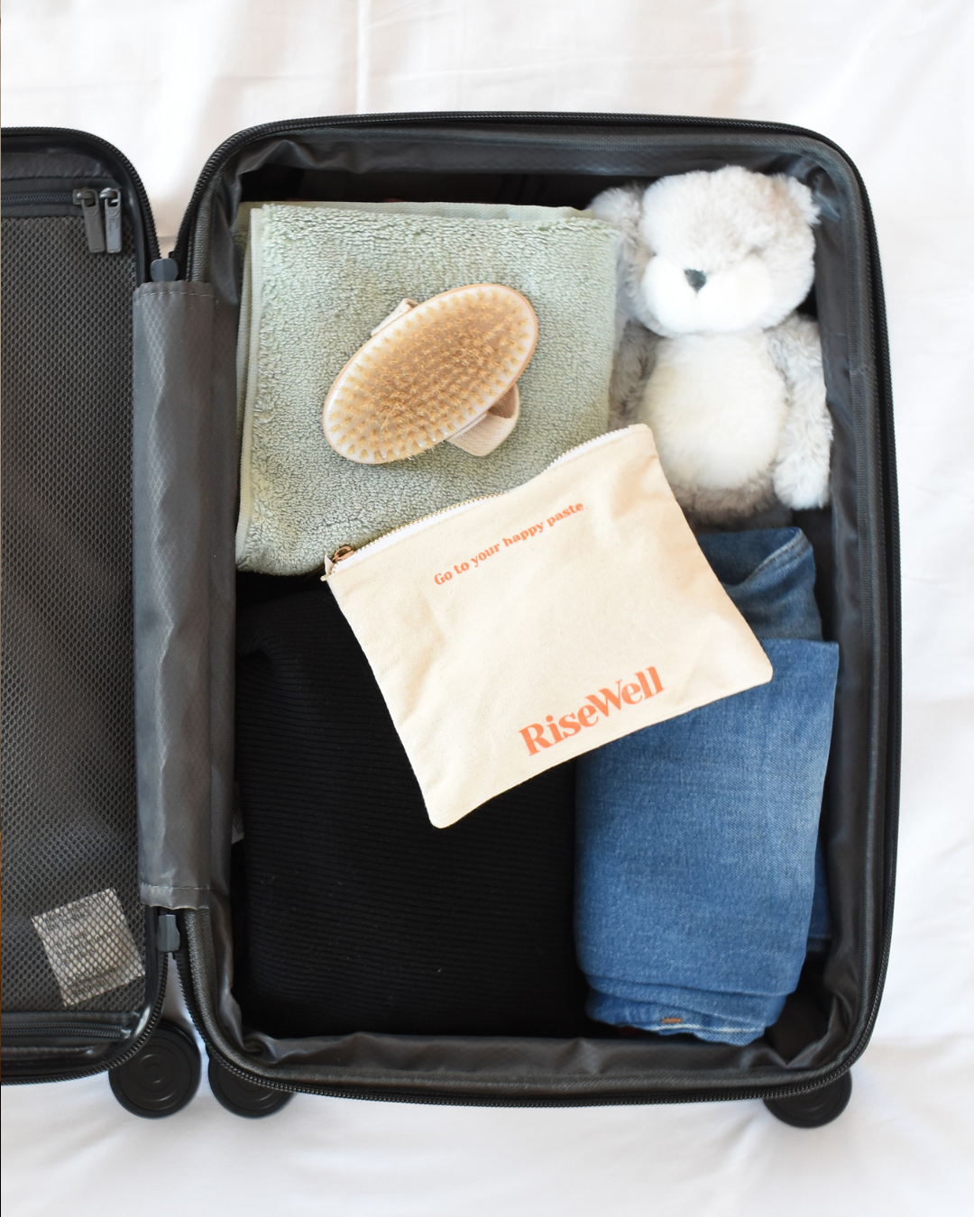 RiseWell travel products in an open suitcase with folded clothes