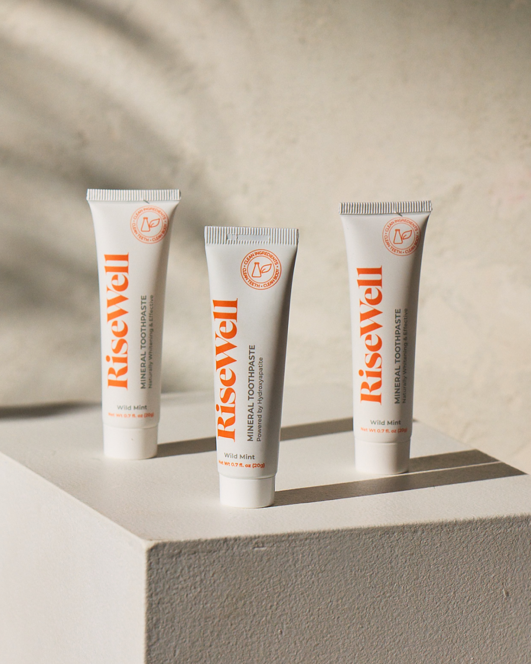 Three tubes of RiseWell toothpaste on a neutral background