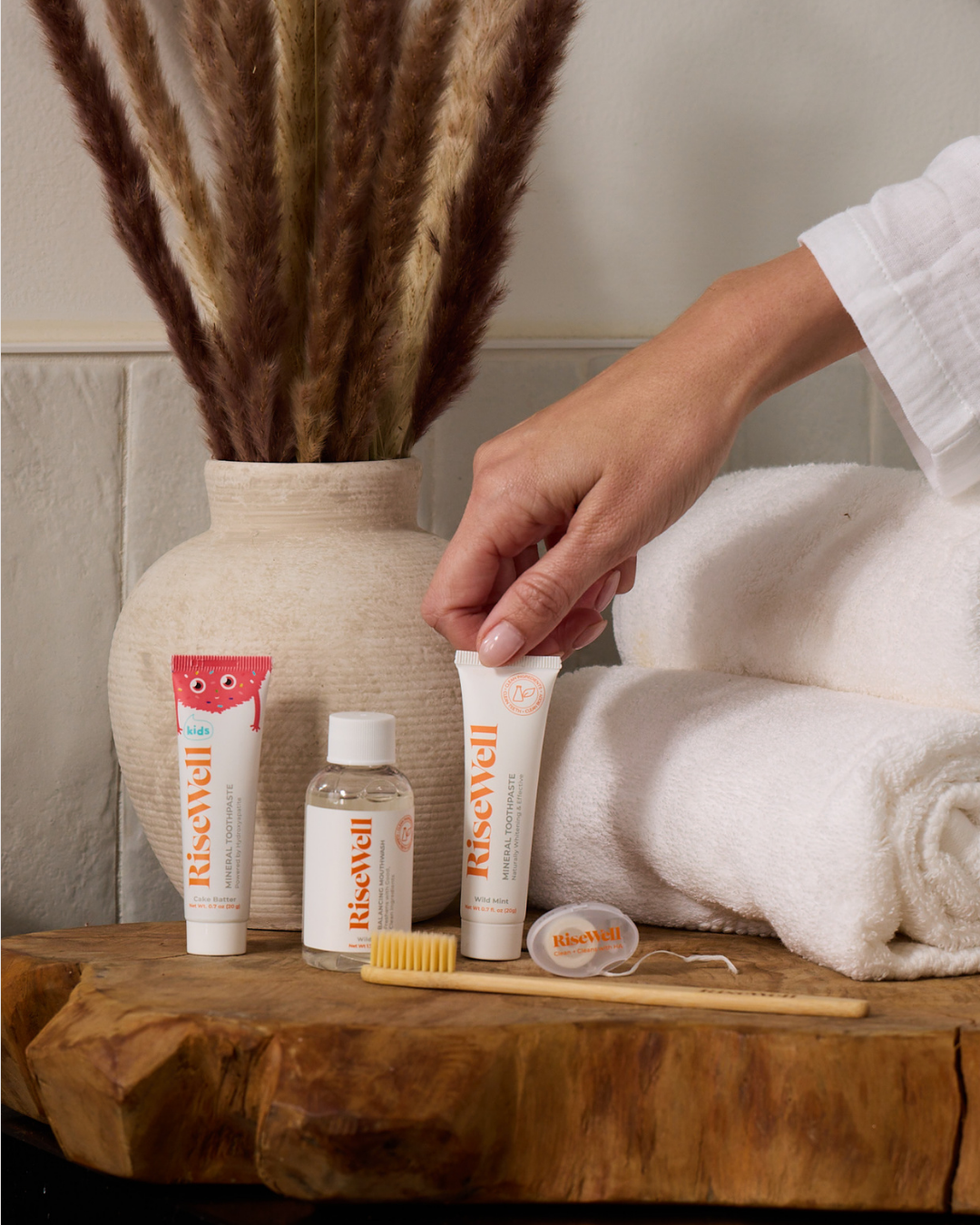 Riswells skincare products on a wooden surface with towels and a vase in the background