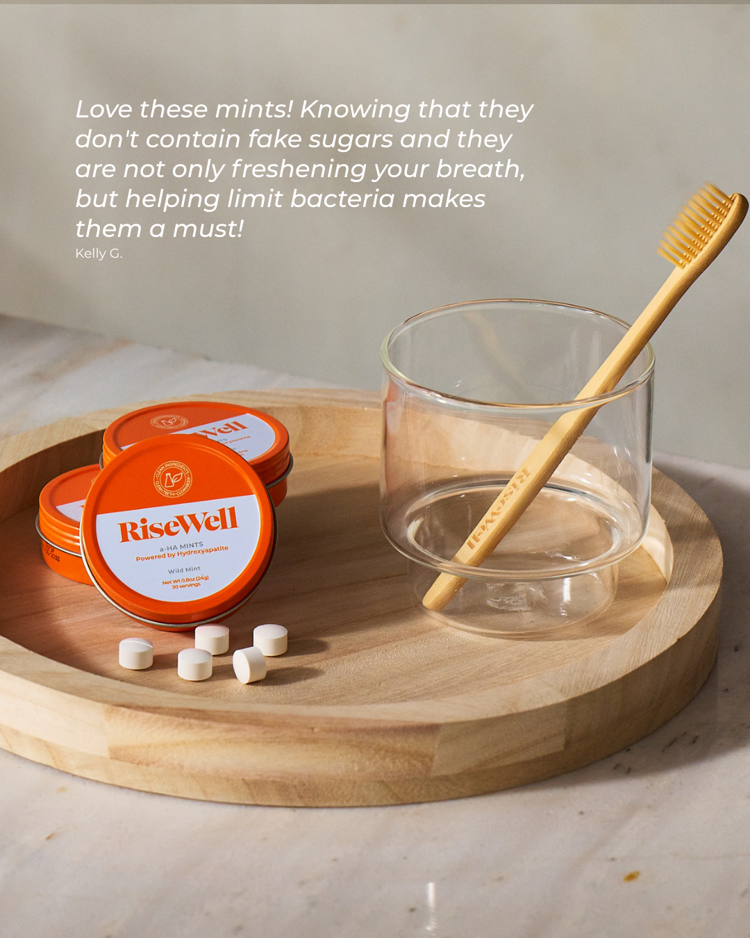 RiseWell mints on a wooden tray with a glass and toothbrush, featuring a customer review.